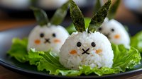 Cute rice balls shaped as bunny faces with carrot noses and nori details, garnished with lettuce leaves and asparagus ears on black plate, creative Asian food styling.