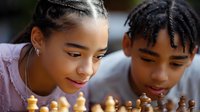 Young African American teenagers playing chess together, focused on game strategy with genuine expressions of concentration and enjoyment during competitive match.