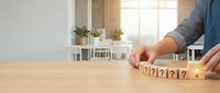 Business person arranging wooden question mark blocks on desk in bright modern office, concept for problem solving and decision making.