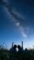 Two children lying on grass pointing at spectacular Milky Way galaxy stretching across starry night sky in cosmic wonder and astronomical exploration.