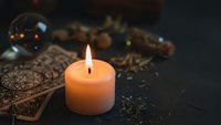 Burning candle with tarot cards and crystal ball creating mystical fortune telling atmosphere for spiritual guidance and divination practices.