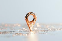 Rose gold location pin marker on glittery surface with soft bokeh background, modern minimal composition for business and travel concepts.