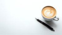Coffee cup with latte art and black pen on white background for business workspace design and office branding materials.