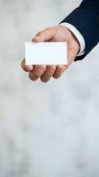 Businessman in dark suit holding blank white business card, ready for contact information or branding mockup design.