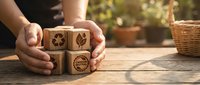 Person with medium skin tone holding wooden blocks with environmental and recycling symbols, promoting sustainability and eco-friendly practices for educational or corporate messaging.