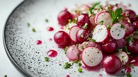 Fresh radish and cherry salad with herbs and black pepper seasoning served on speckled ceramic plate for healthy eating and gourmet cooking concepts.