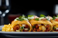 Mexican enchiladas filled with meat and cheese, garnished with fresh herbs and served with french fries on dark plate, close up view with blurred background.