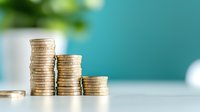 Decreasing stacks of golden coins on white surface against turquoise background, representing financial decline, savings reduction and investment loss concept.