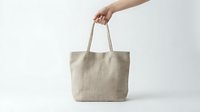 Natural linen tote bag held by female hand against white background, eco-friendly reusable shopping bag for sustainable lifestyle and zero waste living.