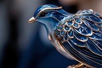 Metallic blue and silver decorative bird figurine with intricate feather pattern detail and elegant design captured in macro photography against dark background.