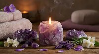 Spa wellness setup with amethyst crystal candle holder, lavender flowers, towels and gemstones creating relaxing aromatherapy atmosphere for meditation.