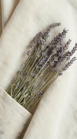 Dried lavender bunch tucked into a linen fabric pocket, soft neutral tones, natural aromatherapy and wellness styling concept.