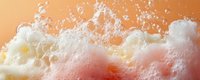 Frothy soap bubbles and foam texture against orange background creating dynamic abstract pattern with white suds and delicate bubble formations.