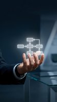 Businessman hand presenting glowing flowchart diagram with connected boxes showing business process workflow and organizational structure concept.