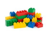 Colorful plastic building blocks in red, blue, yellow, and green arranged in stacks and scattered composition. Isolated on white background, ready for design use on educational materials, toy packaging, and children's content.