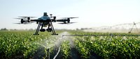 Agricultural drone spraying crops in field with irrigation system in background, precision farming technology.