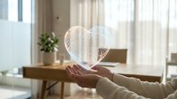 Young woman holding glowing heart-shaped hologram in modern home office with natural light, representing digital love, technology connection, and future innovation for web and app design.