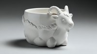 White ceramic cow-shaped mug with decorative details on neutral background for kitchen and dining concepts.