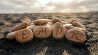 EMDR therapy concept with wooden stones on beach sand at sunset representing eye movement desensitization and reprocessing treatment for trauma healing.