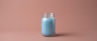 Blue smoothie or protein shake in glass mason jar on pink background for healthy lifestyle and fitness nutrition concepts.