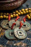Ancient Chinese feng shui coins with red string and wooden prayer beads on rustic wooden background, symbolizing wealth, prosperity and good fortune.