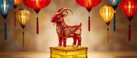 Golden goat sculpture with ornate patterns on pedestal surrounded by colorful traditional lanterns for Chinese New Year celebration and festive decor.