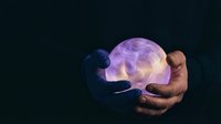 Glowing jellyfish held in human hands against dark background, showcasing bioluminescent marine life and underwater wonder for educational and nature content.