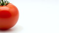 Fresh red ripe tomato with green stem on clean white background. Organic healthy vegetable ingredient for cooking and nutrition concepts.