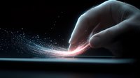 Finger touching glowing surface creating magical light trail effect with sparkling particles against dark background, digital transformation concept.
