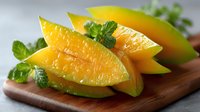 Fresh ripe mango slices with mint leaves on wooden cutting board. Tropical fruit preparation for healthy snacks, smoothies and desserts.