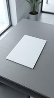 Blank white paper sheet on modern gray desk in minimalist office workspace with plant for business presentations and creative projects.