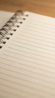 Open spiral notebook with blank lined pages on wooden desk surface for writing notes and planning tasks.