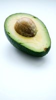 Fresh ripe avocado half with pit on white background isolated for healthy cooking and nutrition content.