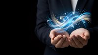 Businessman in dark suit holding glowing blue digital wave with light particles and energy effects in open palms against black background for technology and innovation concepts.
