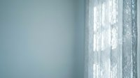 Soft morning light filters through delicate lace curtains in a serene room with pale blue walls, creating a calm, peaceful atmosphere suitable for wellness and lifestyle content.