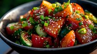 Fresh watermelon poke bowl with cucumber, sesame seeds and green onions served in black ceramic bowl, bright healthy summer food on dark background.