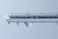 Water droplets forming on metal surface with condensation beads creating natural moisture pattern for scientific and industrial applications.