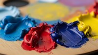 Colorful acrylic paint blobs on wooden palette with brush creating vibrant artistic workspace for creative projects and fine art painting techniques.