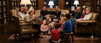 Multi-generational family gathering in elegant library with wooden bookshelves, comfortable seating, and warm lighting for holiday celebrations.