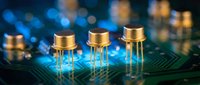 Electronic components with golden leads positioned on circuit board with blue and amber bokeh lights in background, suitable for technology, electronics, and innovation concepts.