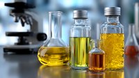 Laboratory glassware with yellow and amber liquids on blurred scientific background with microscope, research and analysis concept for chemistry studies.