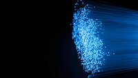 Blue fiber optic cables with glowing light particles streaming through dark background for technology and communication concepts.