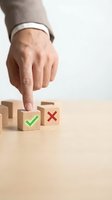 Businessman hand pointing to wooden block with green checkmark choosing yes over red cross, decision and approval concept.