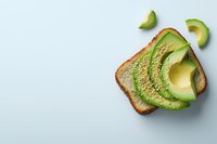 Fresh sliced avocado on toasted bread with sesame seeds, arranged on light blue background. Minimalist breakfast composition with copy space.