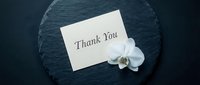 Elegant thank you card with white orchid flower on dark slate background, conveying gratitude and appreciation for events and celebrations.