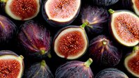 Fresh ripe purple figs cut in half showing juicy red flesh and seeds on dark background, organic fruit composition with water drops for food design.