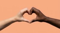 Two diverse hands forming heart shape symbol against coral background representing unity, love, friendship and racial harmony in multicultural society.