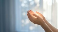 Open hands reaching toward bright light with soft bokeh background creating spiritual and hopeful atmosphere for wellness and meditation concepts.