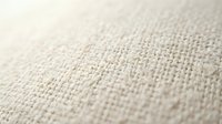 Natural beige linen fabric texture with detailed weave pattern. Close-up macro shot showing textile fibers and organic material structure for backgrounds.