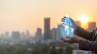 Professional businessman holding glowing digital hologram sphere over urban skyline at sunset representing innovation technology and future business solutions.